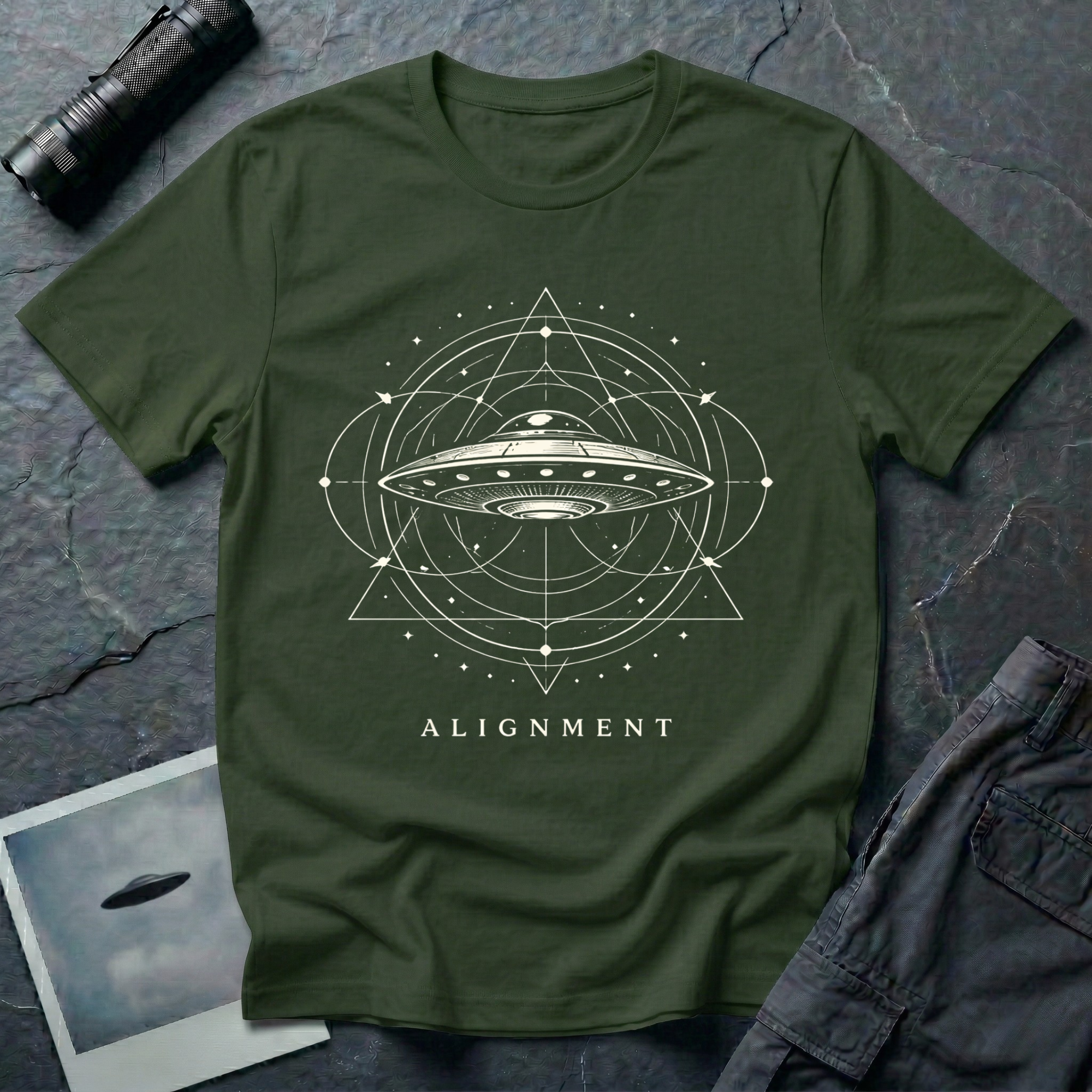 Alignment sacred geometry UFO t-shirt — flying saucer at the centre of a cosmological diagram with triangles and orbital rings in cream on green cotton tee