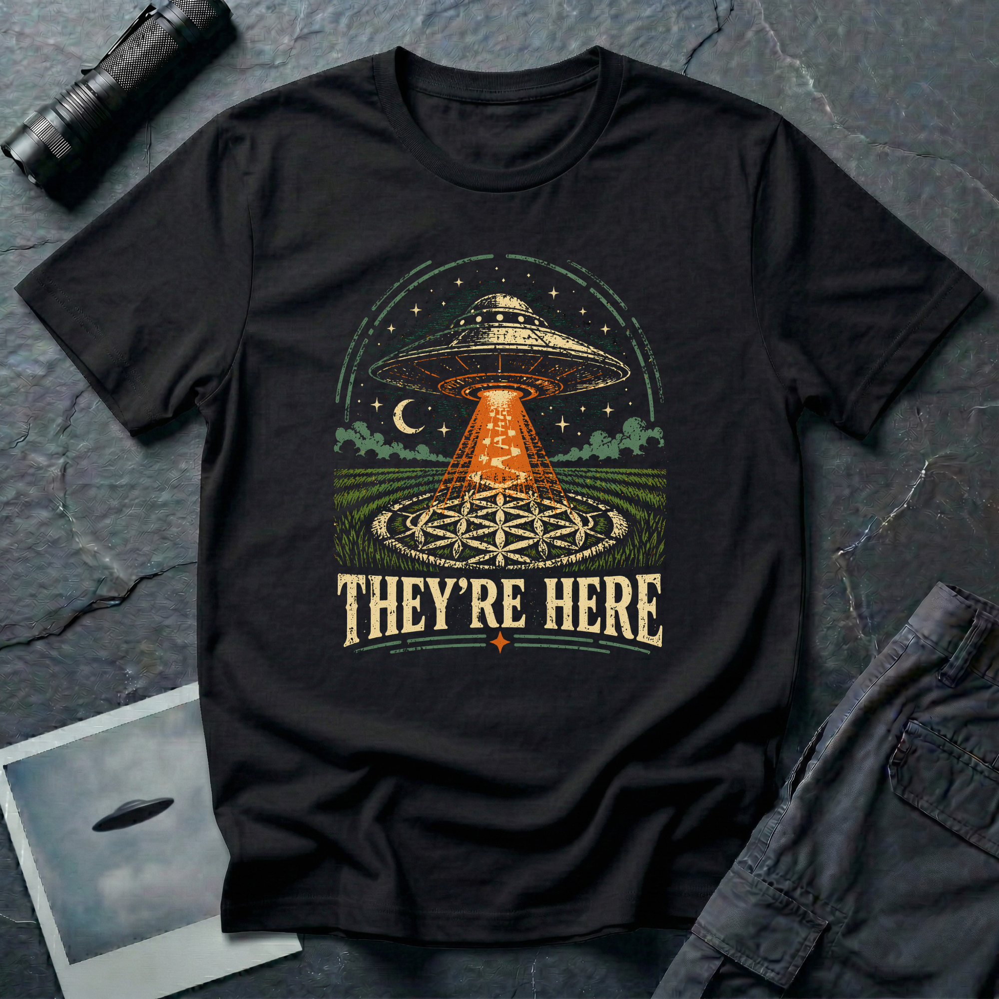 They're Here crop circle UFO t-shirt — flying saucer beaming over Flower of Life crop formation on black unisex cotton tee