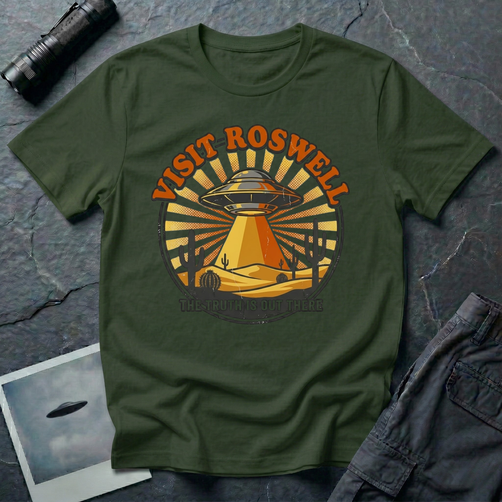 Visit Roswell UFO t-shirt — vintage circular tourism badge with flying saucer beaming over desert cacti in rust and mustard tones on green cotton tee