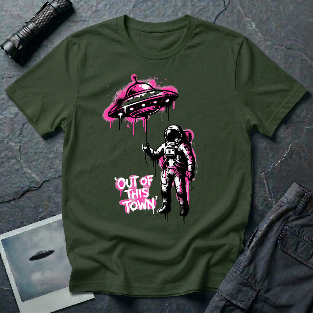 Out of This Town stencil UFO t-shirt — astronaut holding flying saucer like a balloon in Banksy-style street art with hot pink accents on military green cotton tee
