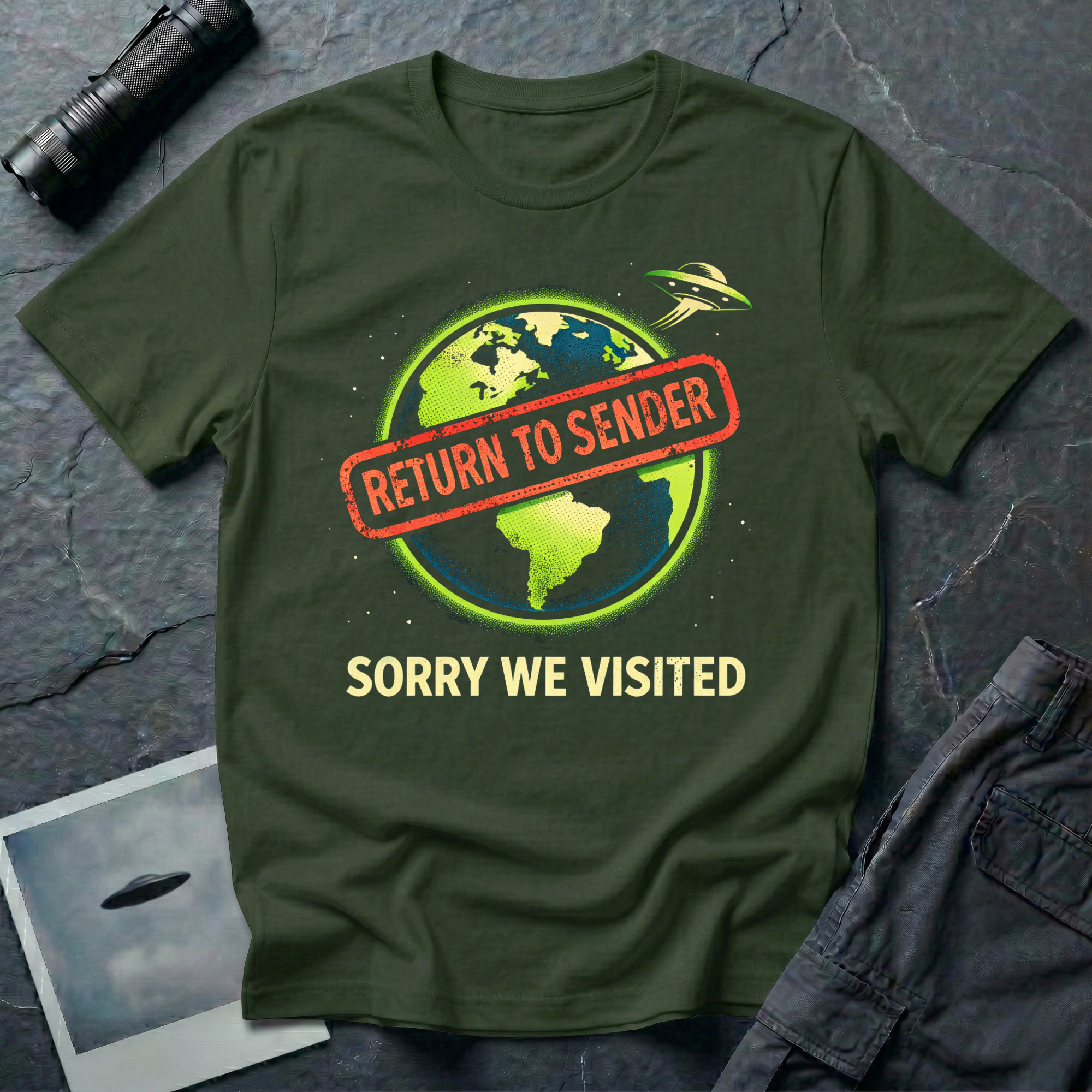 Return To Sender flying saucer t-shirt — UFO leaving Earth with red "return to sender" stamp across the planet and "Sorry we visited" tagline on military green cotton tee