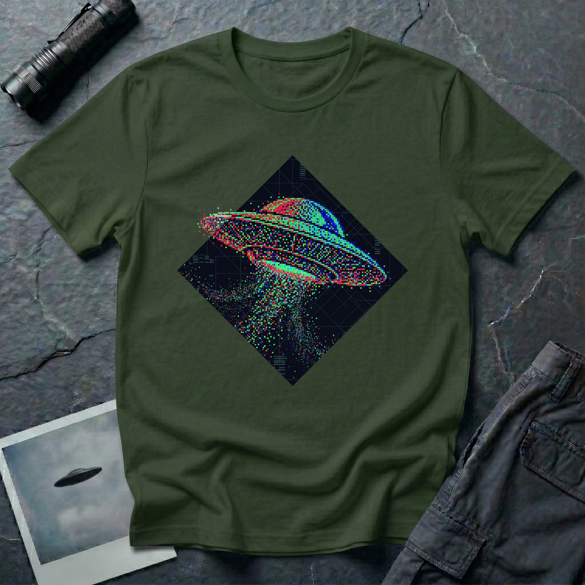 Glitch UFO t-shirt — flying saucer rendered in RGB pixel dots disintegrating inside a dark diamond frame on military green cotton tee