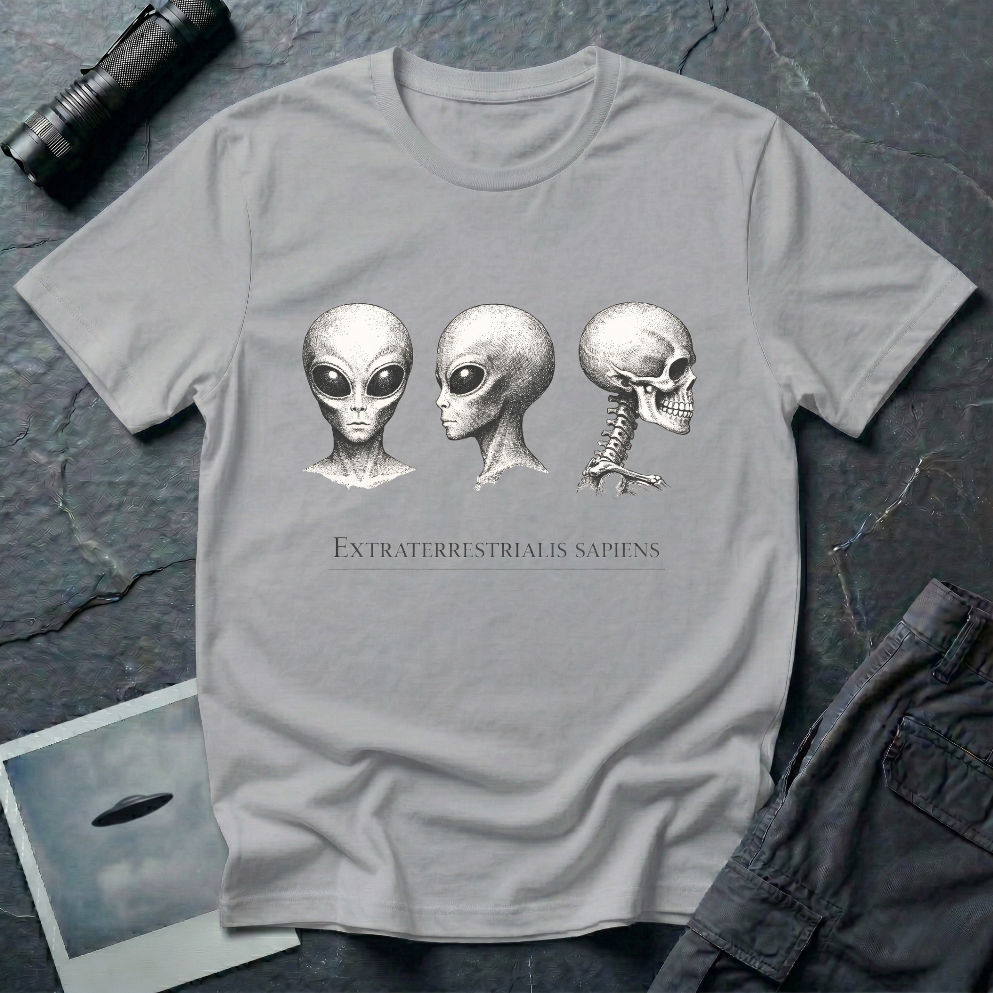 Extraterrestrialis Sapiens ancient aliens t-shirt — three heads in 19th-century anatomical study style with grey alien front and profile views and human skull on grey cotton tee