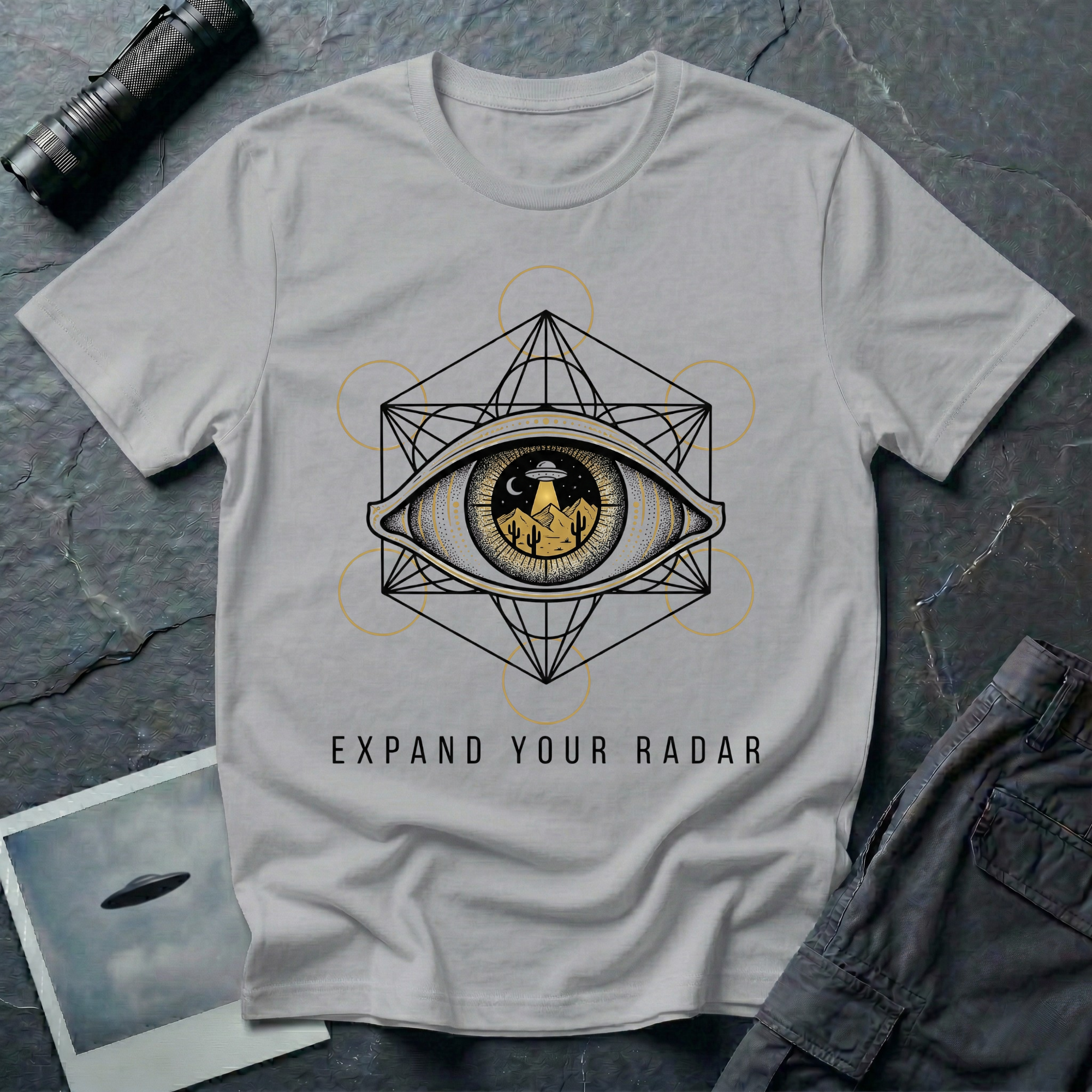 Expand Your Radar all seeing eye UFO t-shirt — sacred geometry frame around an eye containing a desert UFO encounter in gold and black linework on grey cotton tee