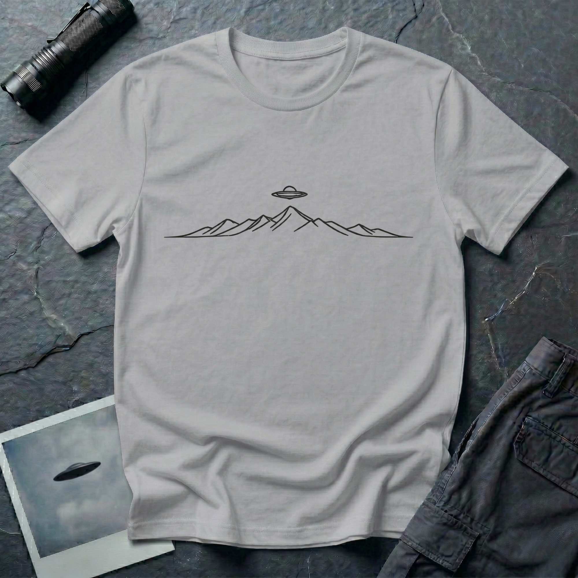 Line Drawing UFO minimalist mountain t-shirt — fine black linework mountain range with small flying saucer above the central peak on grey cotton tee