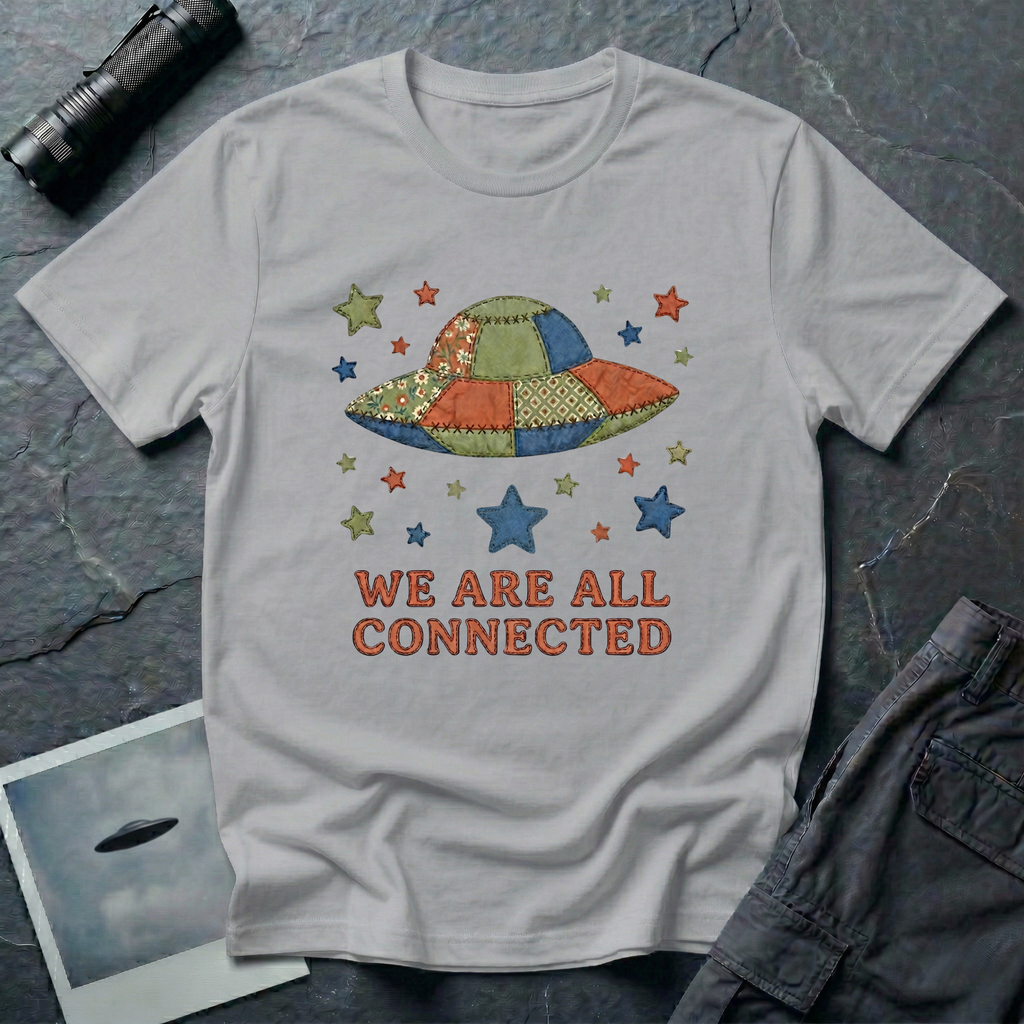 We Are All Connected folk quilt UFO t-shirt — patchwork saucer with cross-stitched fabric panels and stars in rust, navy and olive on grey cotton tee