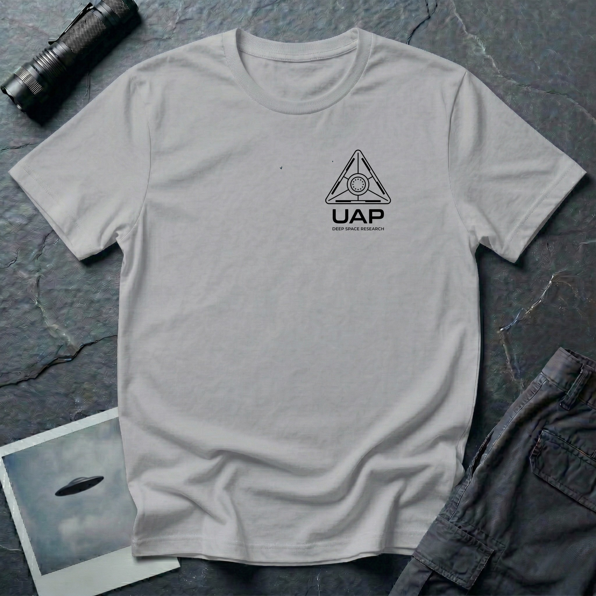 Grey t-shirt with small left-chest black line art geometric triangle UAP mission patch design with the text UAP DEEP SPACE RESEARCH