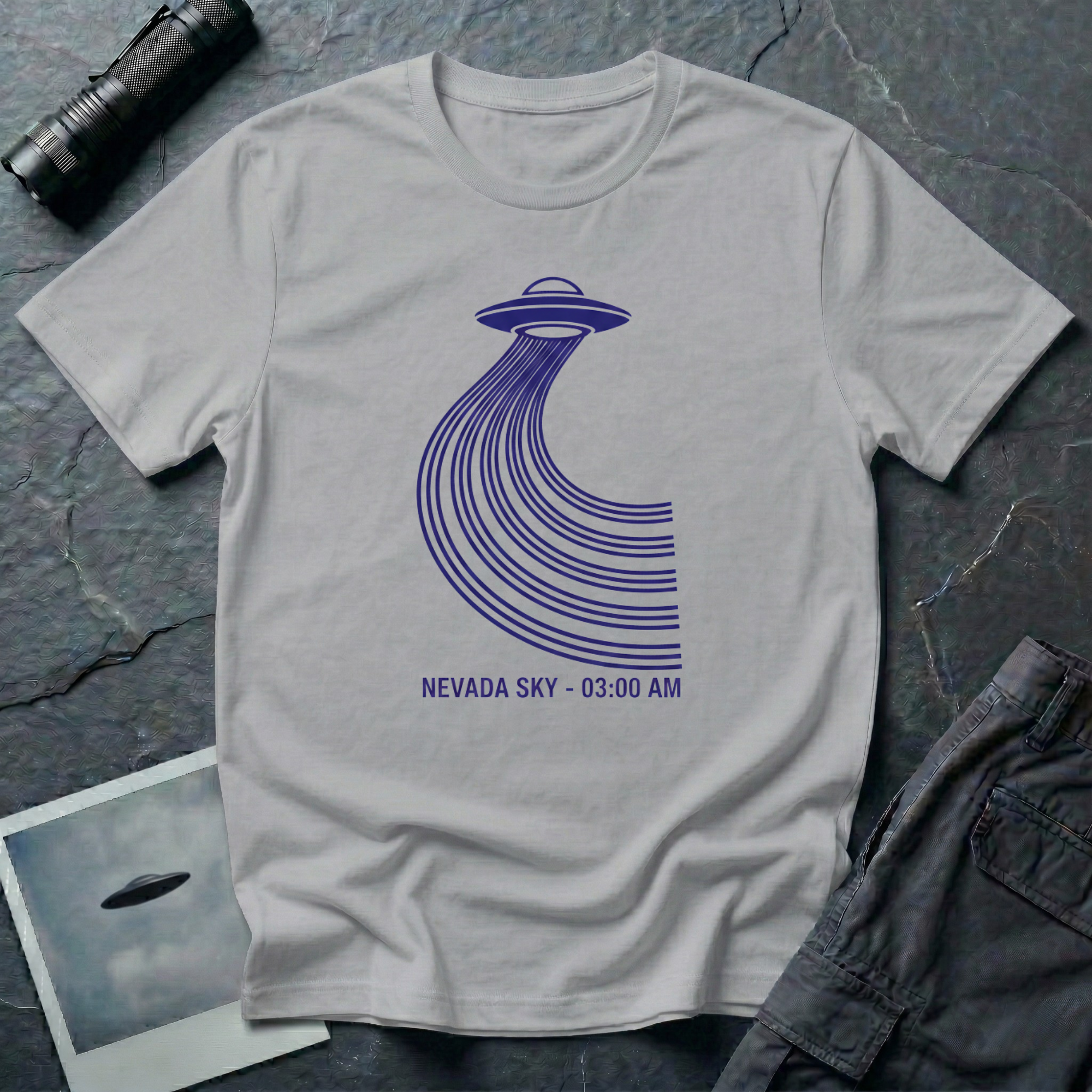 Nevada Sky 03:00 AM UFO sighting t-shirt — navy flying saucer with parabolic trail of parallel lines and timestamp caption on grey cotton tee