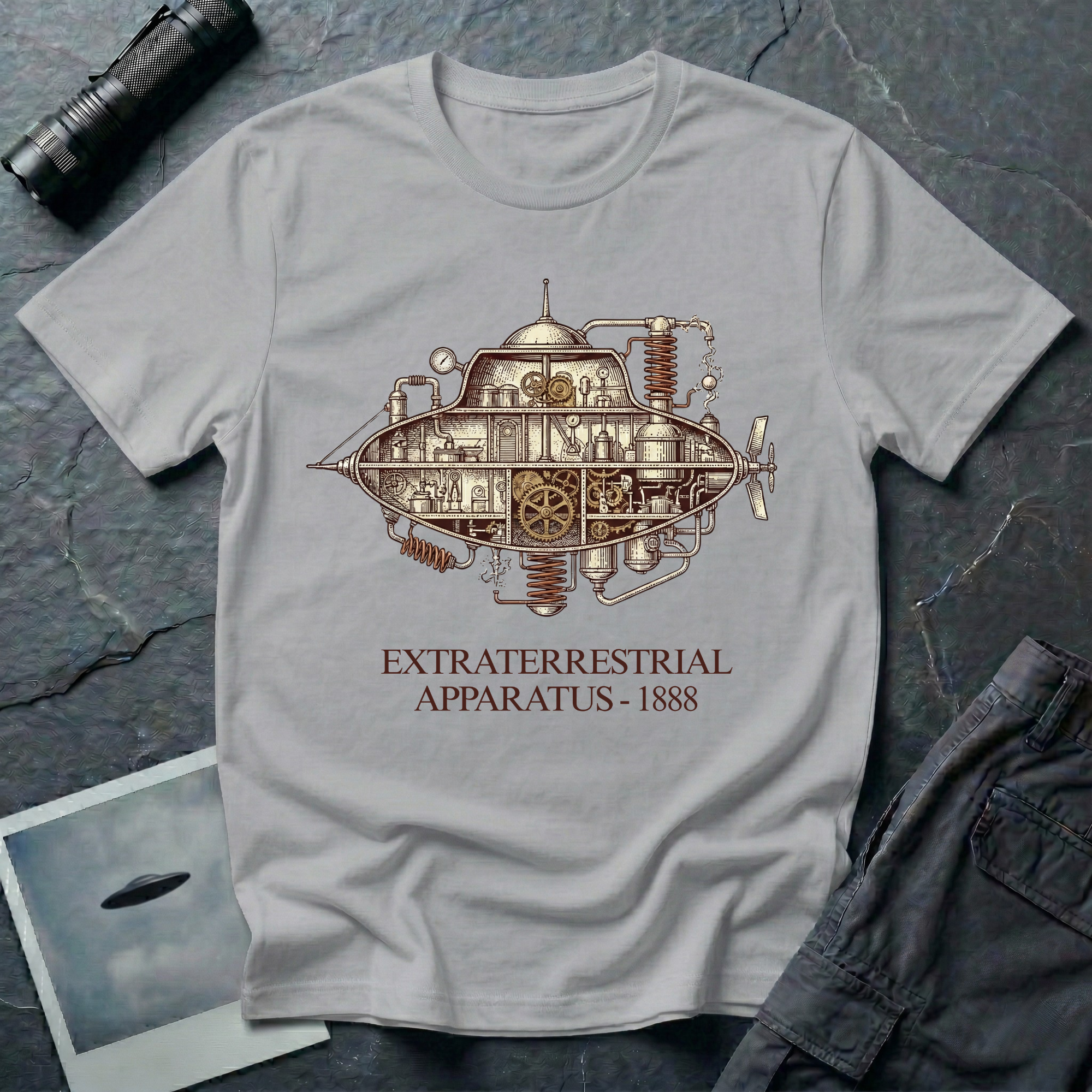 Extraterrestrial Apparatus steampunk UFO t-shirt — Victorian-era airship with exposed brass machinery gears and copper piping with "Extraterrestrial Apparatus 1888" caption on grey cotton tee
