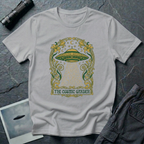The Cosmic Garden Art Nouveau UFO t-shirt — ornate Mucha-style frame with flying saucer and botanical beam in green and gold on grey cotton tee