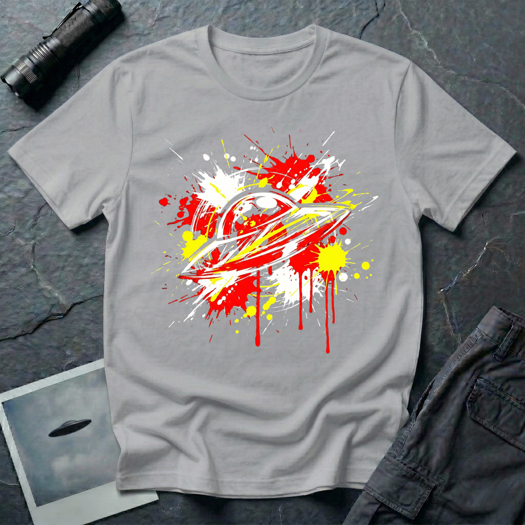 Crash Landing street art UFO t-shirt — flying saucer in explosive red, yellow, and white paint splatter with drips on grey cotton tee