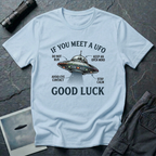 If You Meet A UFO funny UFO t-shirt — flying saucer with deadpan safety instructions on light blue unisex cotton tee