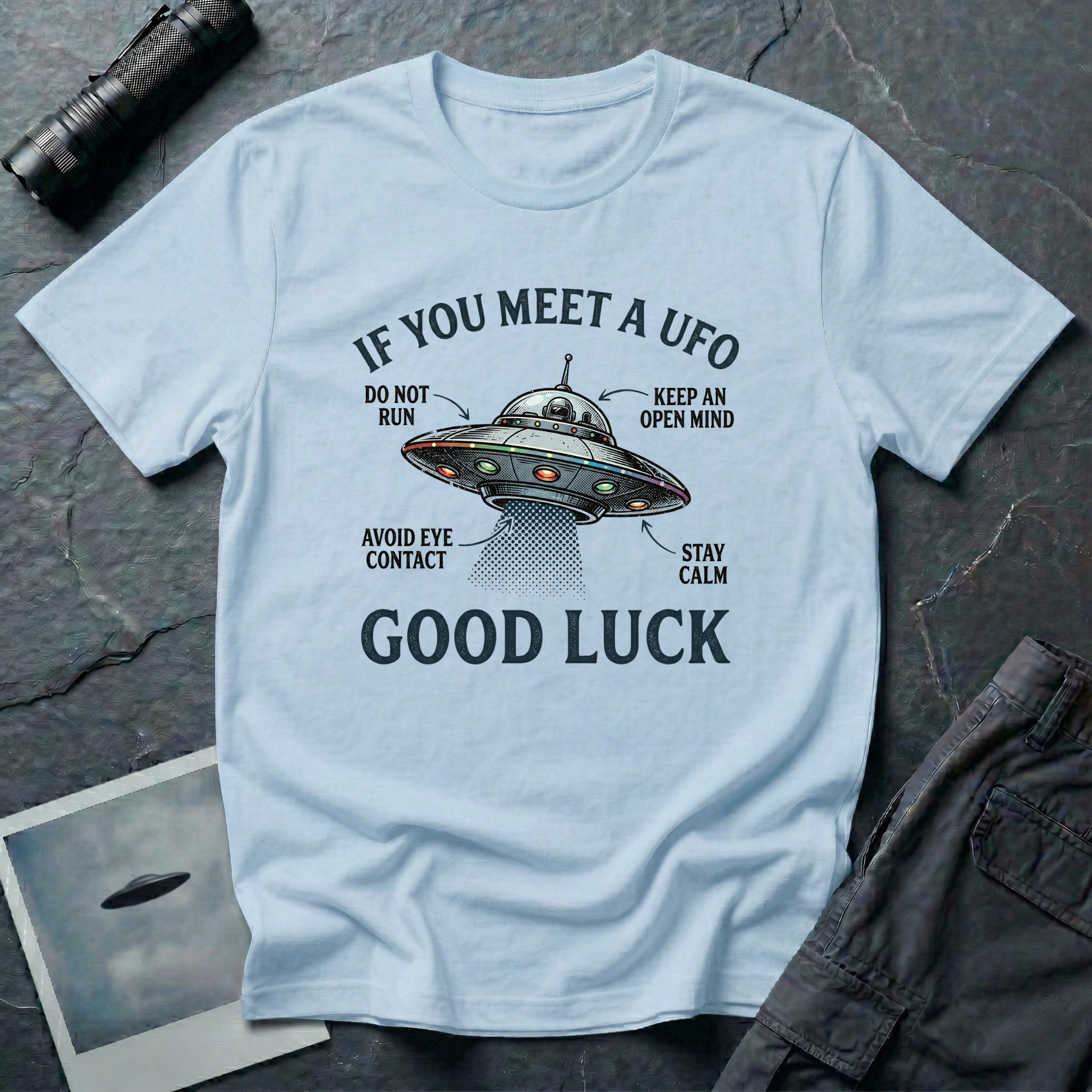 If You Meet A UFO funny UFO t-shirt — flying saucer with deadpan safety instructions on light blue unisex cotton tee