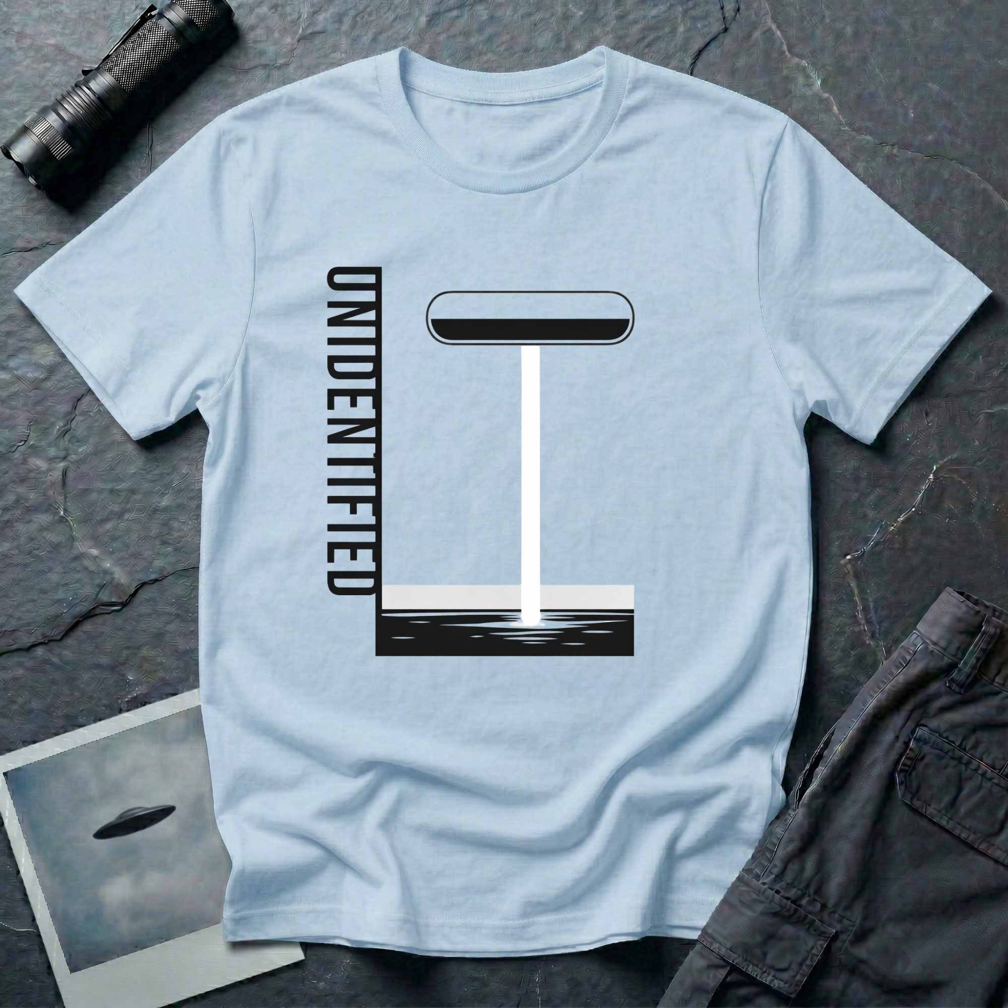 Unidentified graphic design UFO t-shirt — geometric Bauhaus-style saucer with vertical beam and "Unidentified" typography on light blue cotton tee