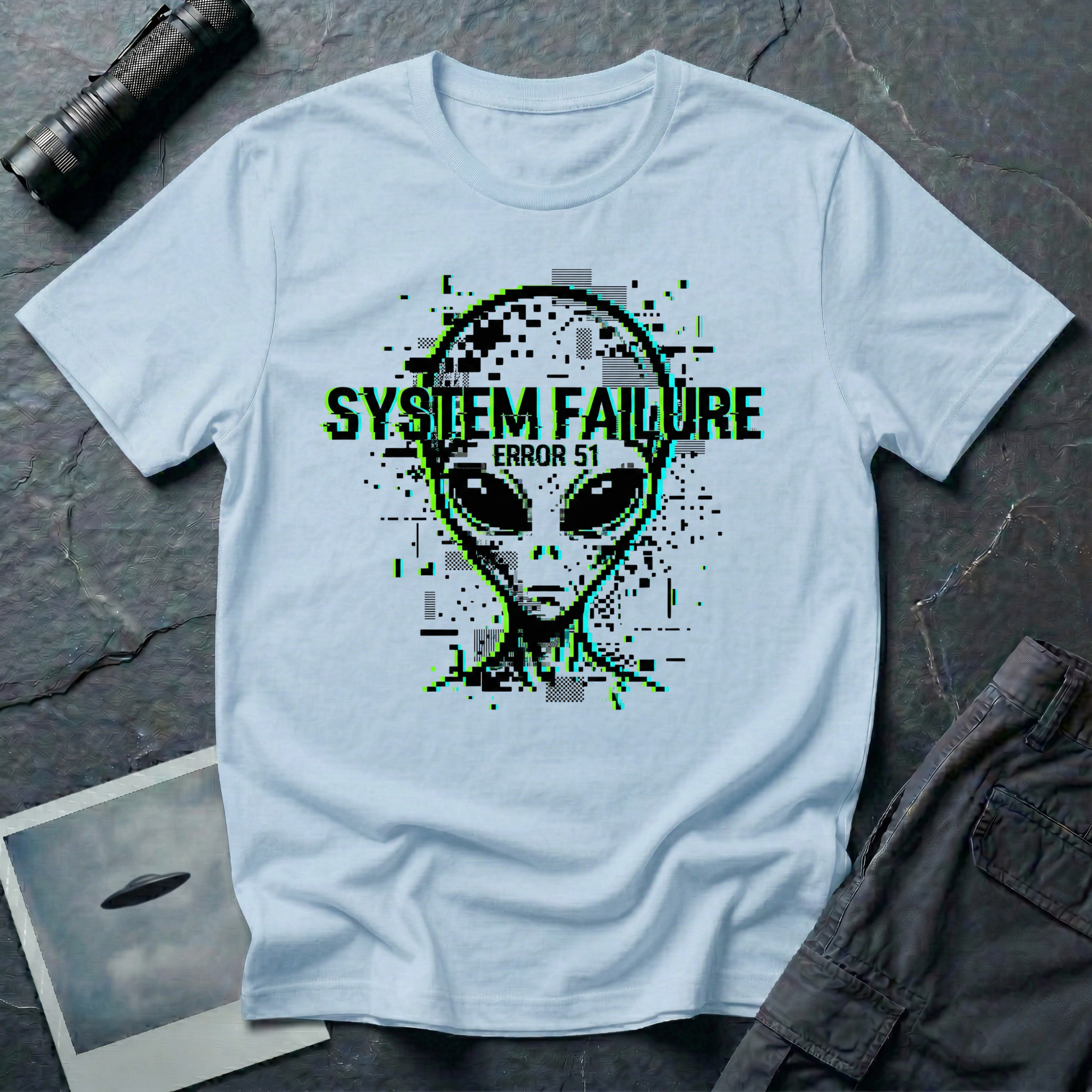 System Failure simulation UFO t-shirt — grey alien head fragmenting into pixel debris with chromatic glitch and "Error 51" on light blue cotton tee