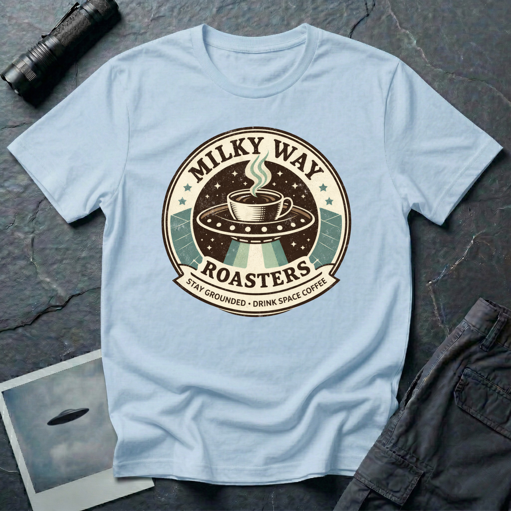 Milky Way Roasters coffee UFO t-shirt — vintage roaster badge with steaming cup on flying saucer and "Stay Grounded Drink Space Coffee" tagline on pale blue cotton tee