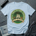Devils Tower UFO t-shirt — vintage distressed National Park badge with the Wyoming monument silhouette, tiny flying saucers and constellations over a starry green sky, "DEVILS TOWER NATIONAL MONUMENT" arc text and "EST. 1906 — CLOSE ENCOUNTERS" banner on light blue cotton tee