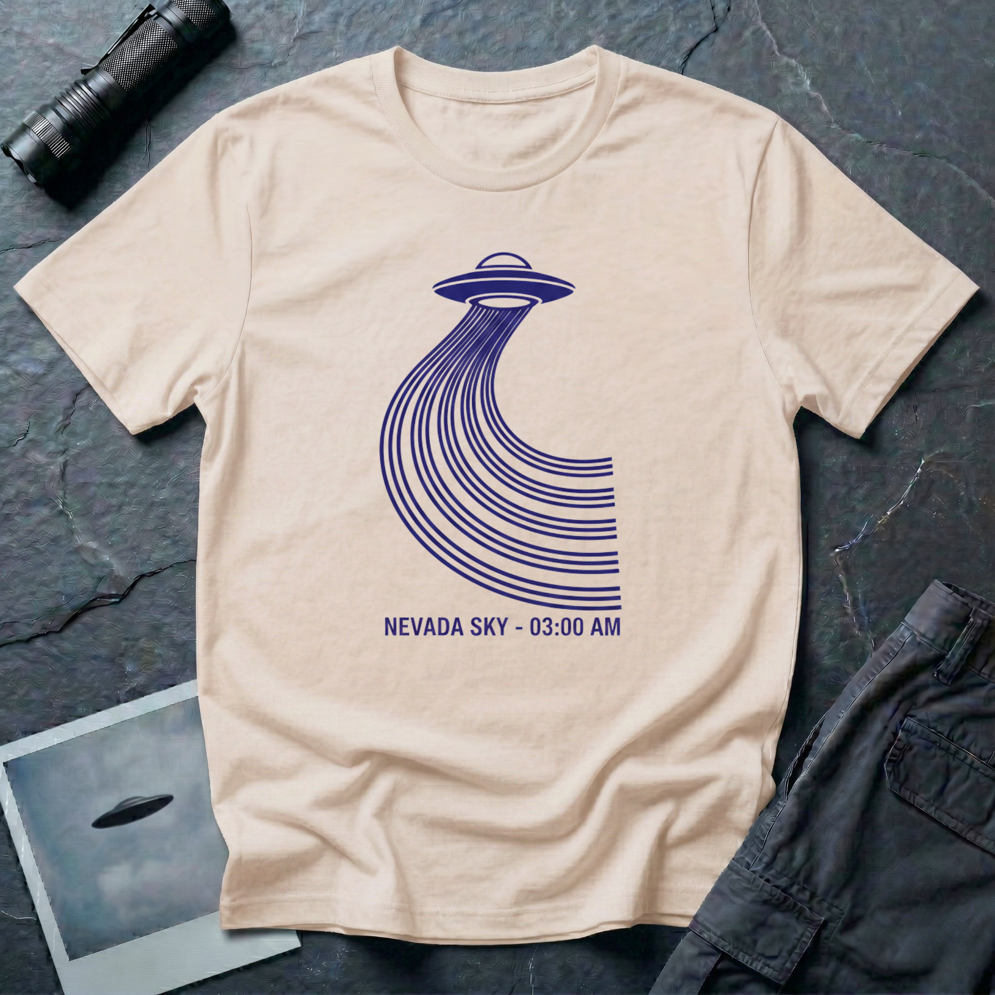 Nevada Sky 03:00 AM UFO sighting t-shirt — navy flying saucer with parabolic trail of parallel lines and timestamp caption on natural cotton tee