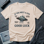 If You Meet A UFO funny UFO t-shirt — flying saucer with deadpan safety instructions on natural unisex cotton tee