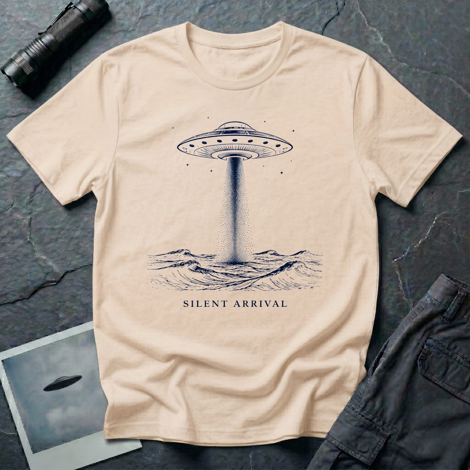 Silent Arrival ocean UFO t-shirt — flying saucer hovering over ocean waves with light beam on natural unisex cotton tee
