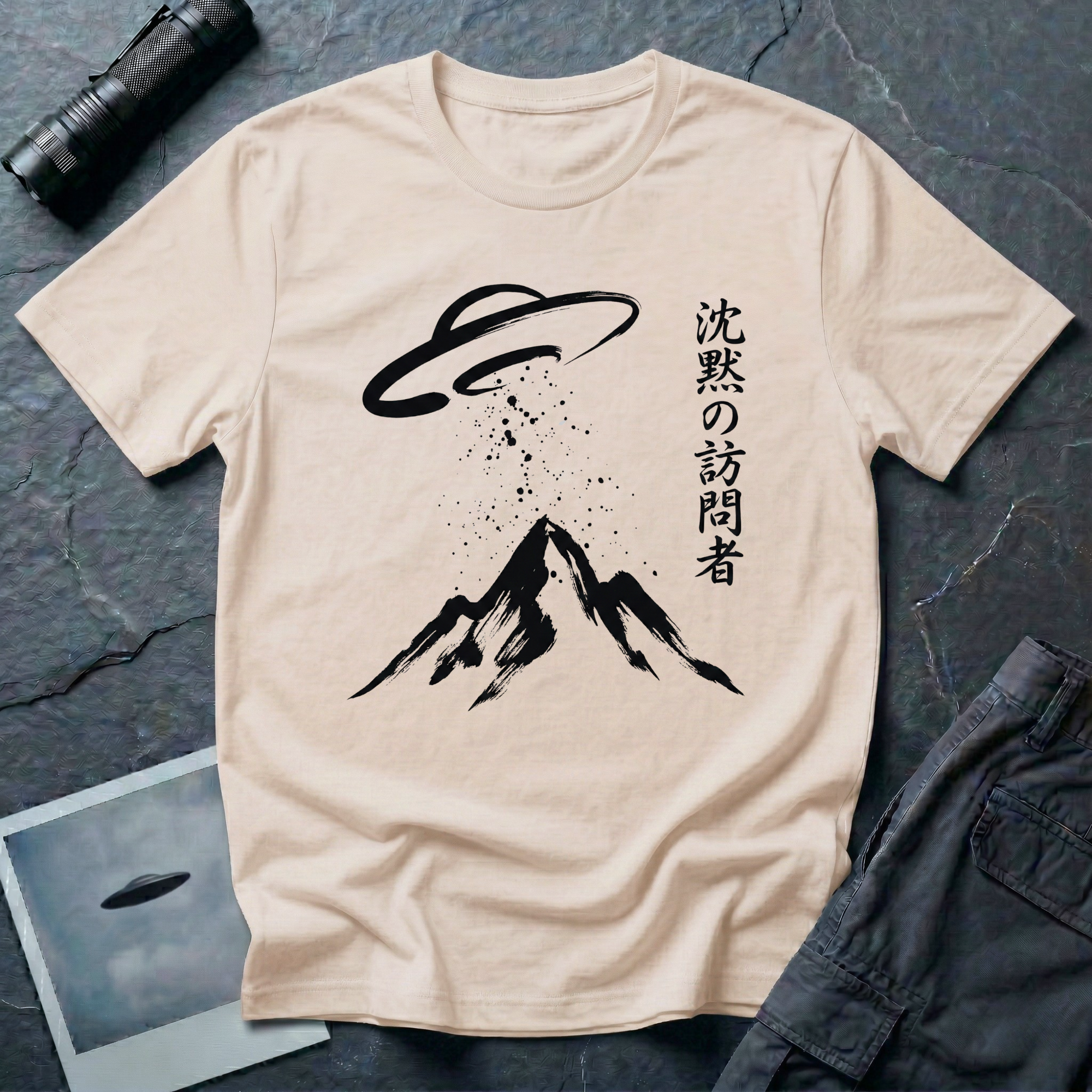 The Silent Visitor sumi-e UFO t-shirt — brush-painted flying saucer over mountain peak with Japanese "silent visitor" calligraphy on natural cotton tee