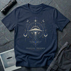 Navy blue t-shirt with a symmetrical celestial UFO illustration featuring crescent moons, four-pointed stars and ornate scrollwork framing a central saucer in gold and blue linework with CELESTIAL PRESENCE caption