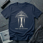 They Are Watching Gothic UFO t-shirt — medieval cathedral fused with flying saucer beaming down on hooded figure in cream line-work on navy cotton tee