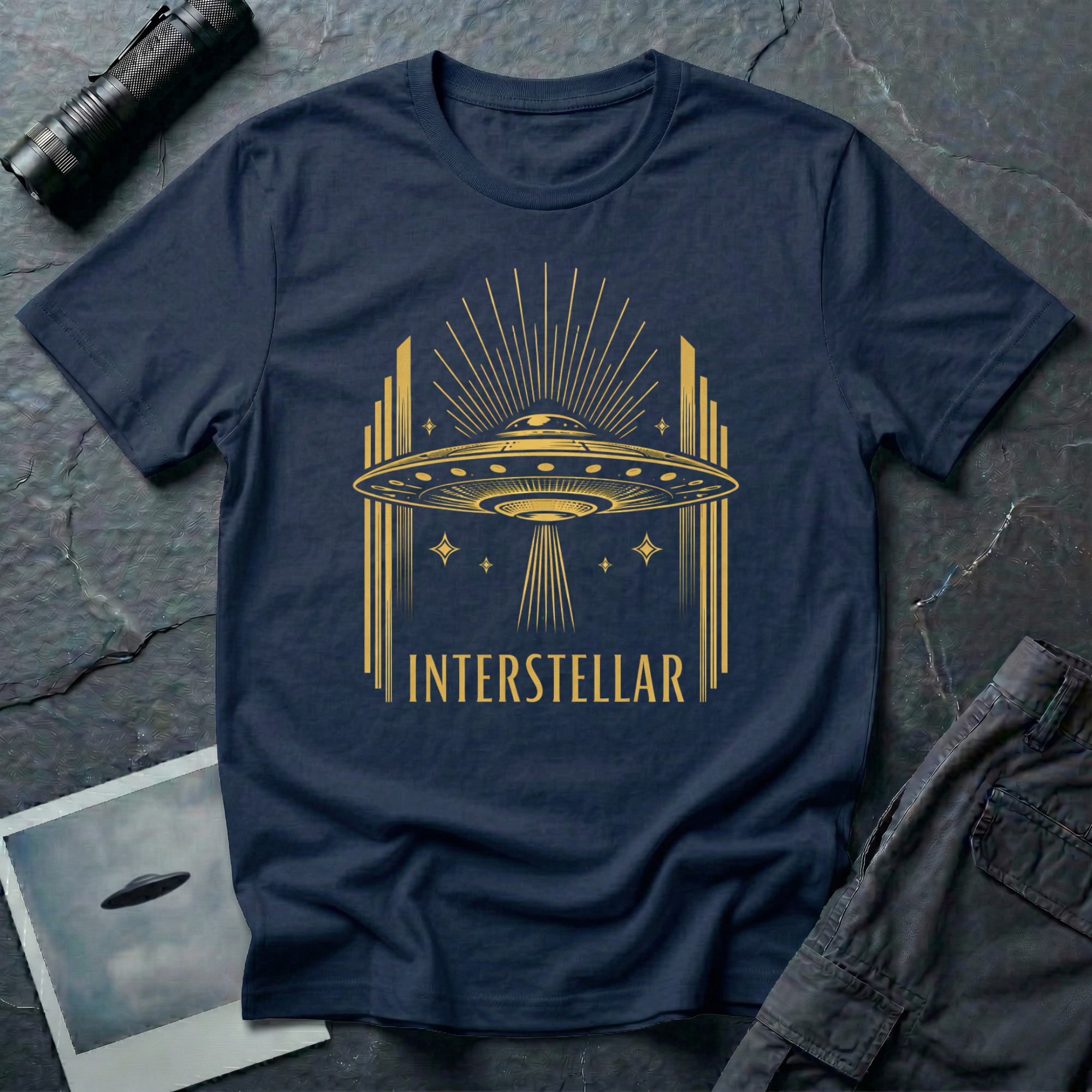 Interstellar Art Deco UFO t-shirt — flying saucer with stepped skyscraper verticals and sunburst rays in gold on navy cotton tee