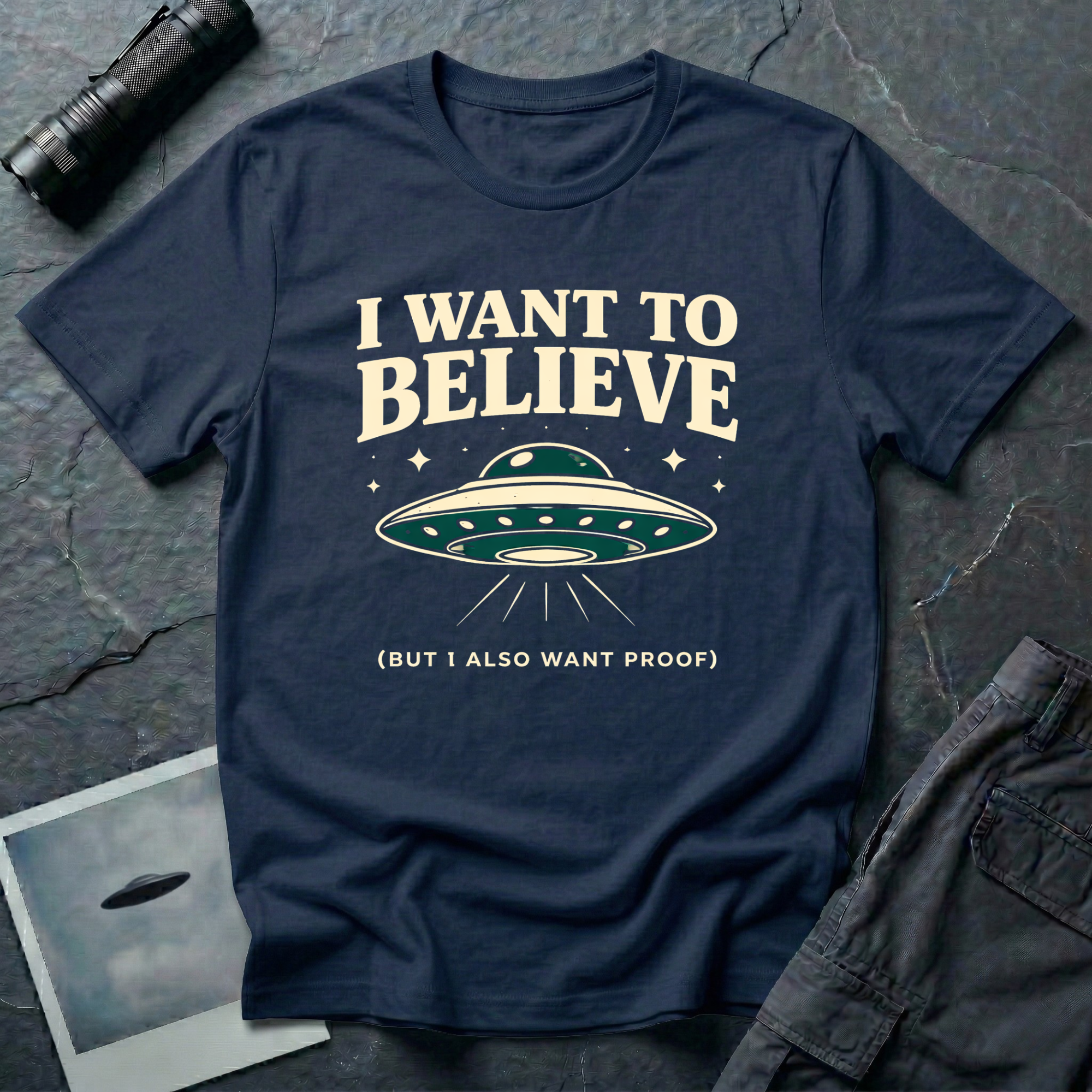 I Want To Believe ironic UFO t-shirt — classic teal saucer with the phrase "I want to believe (but I also want proof)" on navy cotton tee