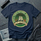 Devils Tower UFO t-shirt — vintage distressed National Park badge with the Wyoming monument silhouette, tiny flying saucers and constellations over a starry green sky, "DEVILS TOWER NATIONAL MONUMENT" arc text and "EST. 1906 — CLOSE ENCOUNTERS" banner on navy cotton tee