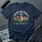 Visitors Are Among Us outdoor UFO t-shirt — flying saucer over mountain range and pine forest on navy unisex cotton tee
