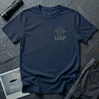 UAP logo t-shirt — small minimalist saucer icon and UAP letters in grey on the upper left chest of navy blue cotton tee
