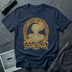 Cosmos Art Nouveau alien t-shirt — green grey alien portrait with large almond eyes and flowing orange hair in ornate gold decorative frame with scrollwork and "Cosmos" banner on navy cotton tee