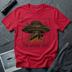 The Wicker Visit folk horror UFO t-shirt — woven wicker flying saucer with antler crown burning in orange flames on red cotton tee