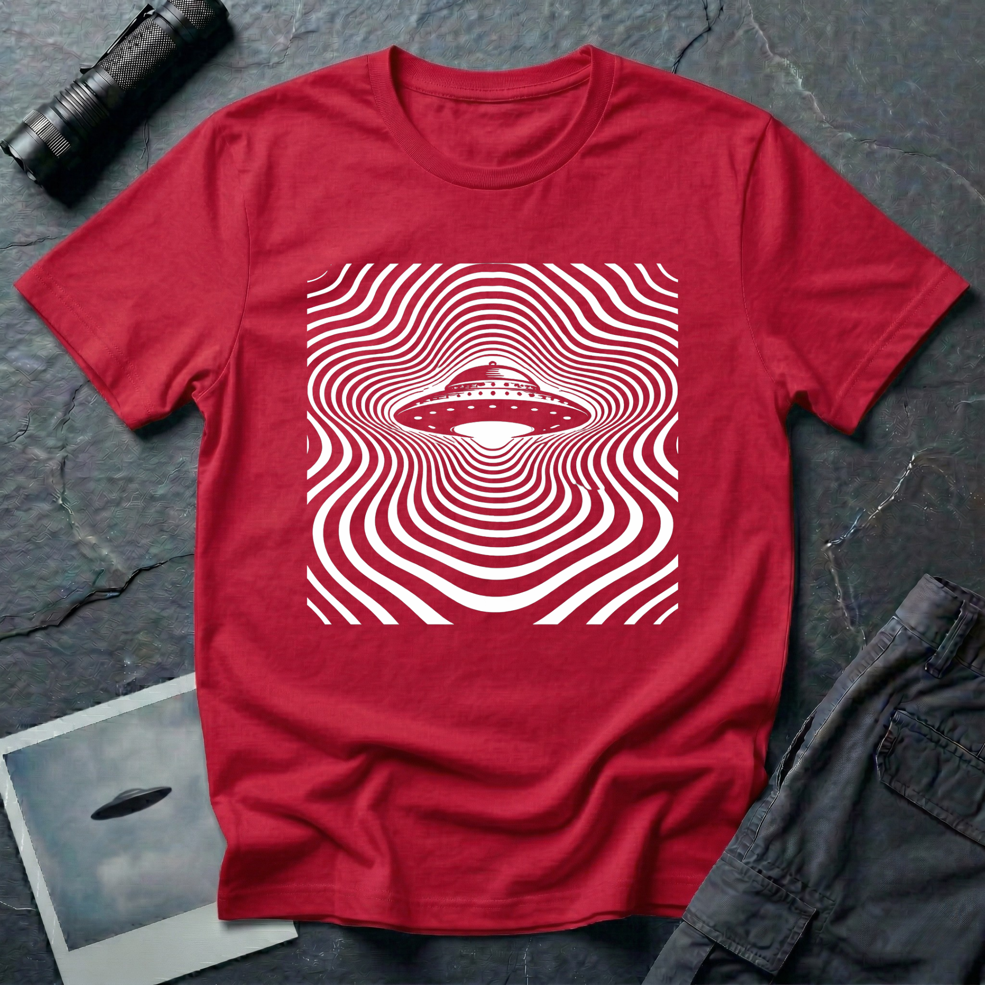 ypnotic op art UFO t-shirt — classic flying saucer at centre of rippling concentric wave-lines distorting around the craft in white on red cotton tee