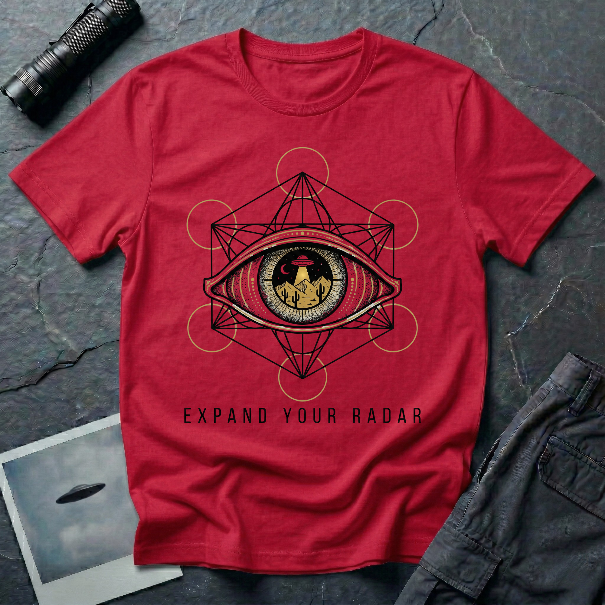 Expand Your Radar all seeing eye UFO t-shirt — sacred geometry frame around an eye containing a desert UFO encounter in gold and black linework on red cotton tee