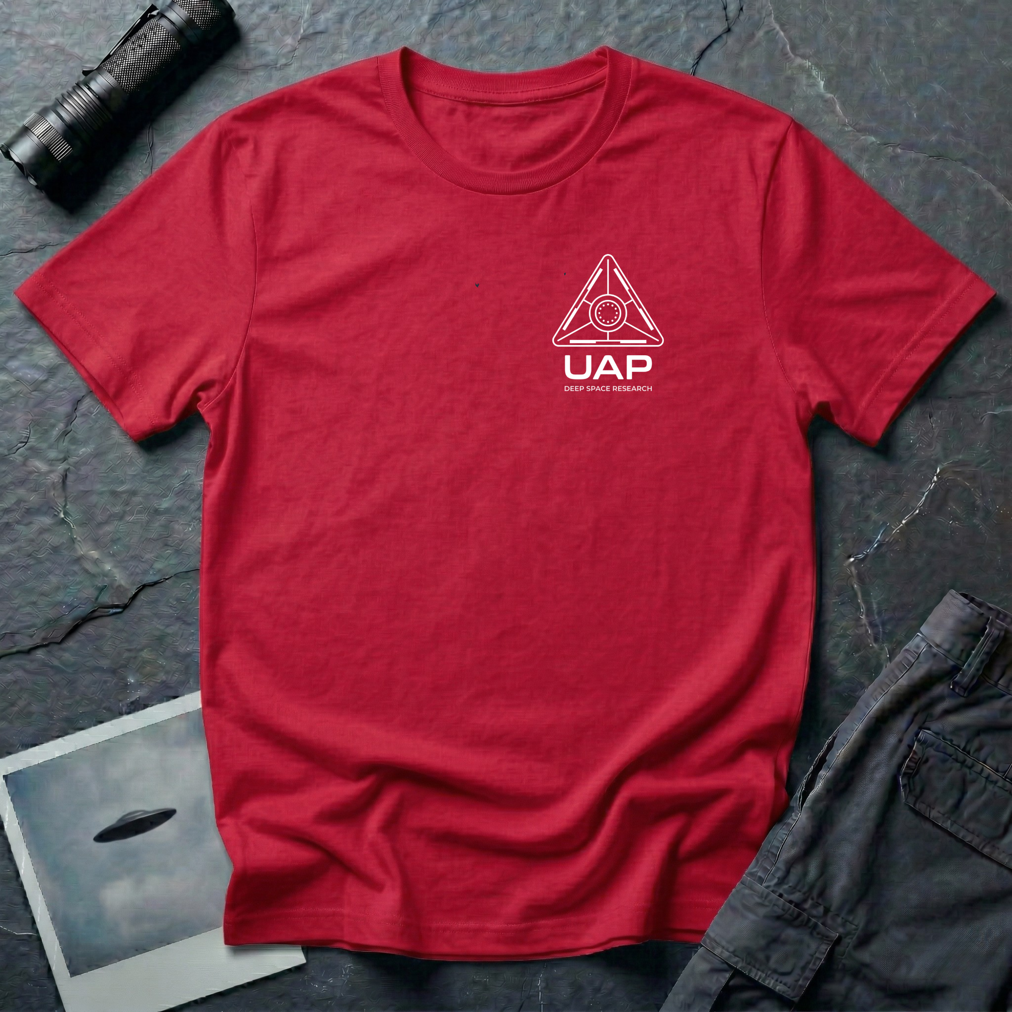 Red t-shirt with small left-chest white line art geometric triangle UAP mission patch design with the text UAP DEEP SPACE RESEARCH