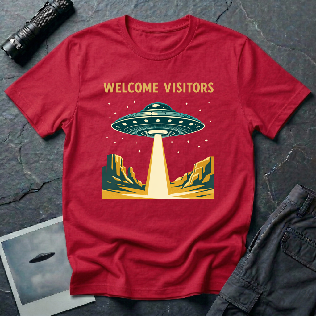 Welcome Visitors Southwest UFO t-shirt — flying saucer beaming down into gold and teal desert canyon landscape with "Welcome Visitors" text on red cotton tee