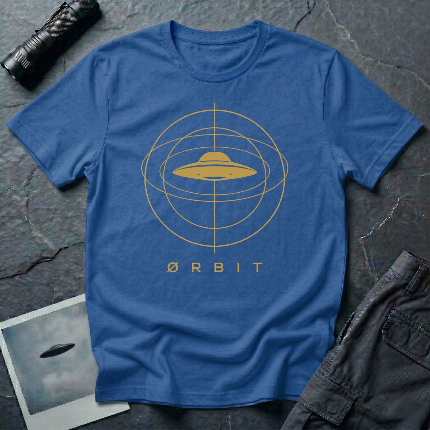Orbit astronomical UFO t-shirt — flying saucer centred in a gold orbital sphere framework with "Ørbit" sans serif typography on royal blue cotton tee