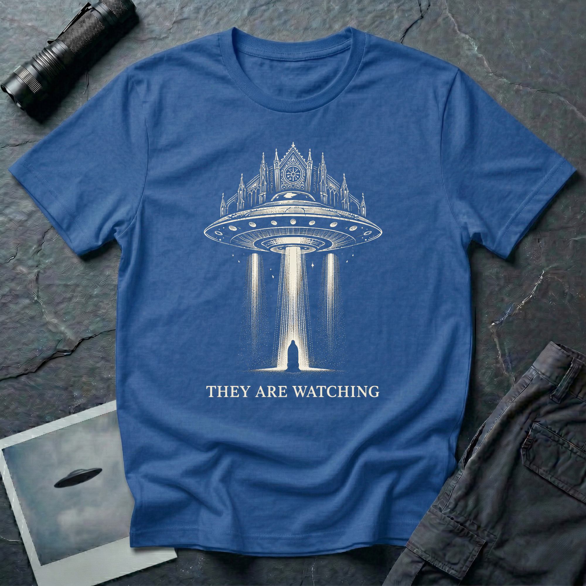 They Are Watching Gothic UFO t-shirt — medieval cathedral fused with flying saucer beaming down on hooded figure in cream line-work on blue cotton tee