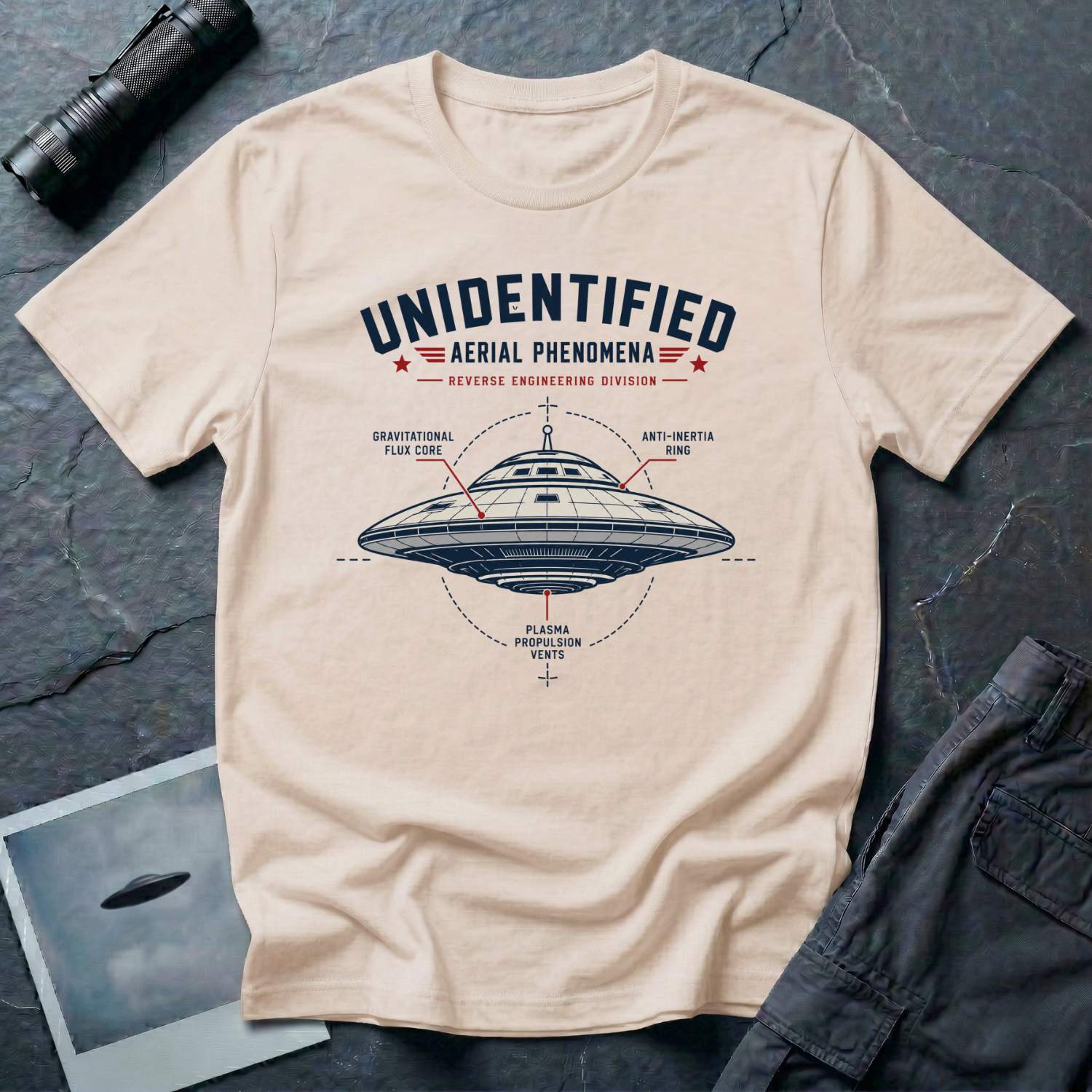Natural t-shirt with military-style UAP Reverse Engineering Division patch featuring an annotated saucer diagram with gravitational flux core anti-inertia ring and plasma propulsion vents callouts