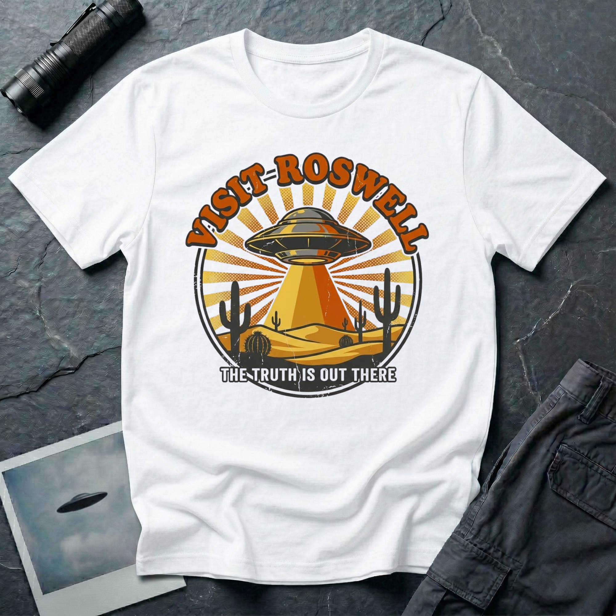 Visit Roswell UFO t-shirt — vintage circular tourism badge with flying saucer beaming over desert cacti in rust and mustard tones on white cotton tee