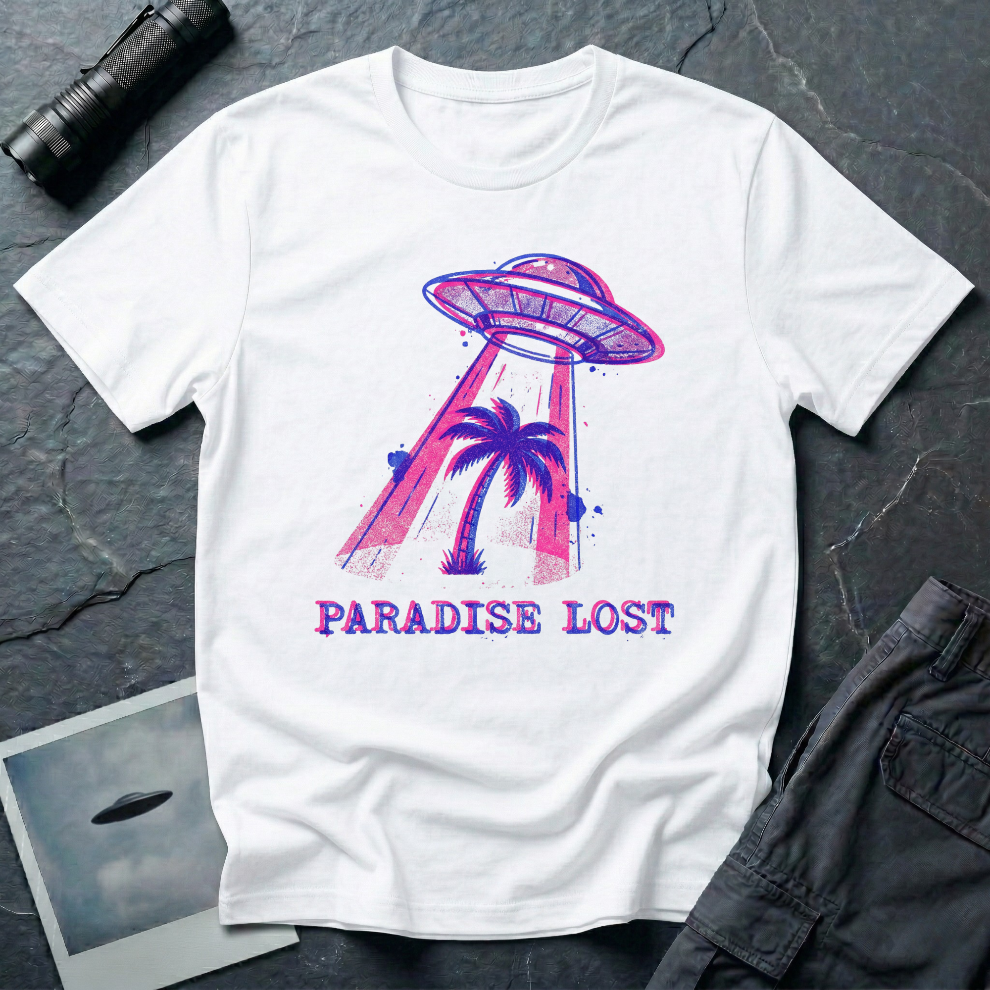Paradise Lost tropical UFO t-shirt — palm tree being lifted into flying saucer tractor beam in pink and blue riso print with "Paradise Lost" caption on white cotton tee