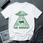 The Harvest dark folklore UFO t-shirt — linocut flying saucer with swirling beam abducting a lone cow in green on white cotton tee