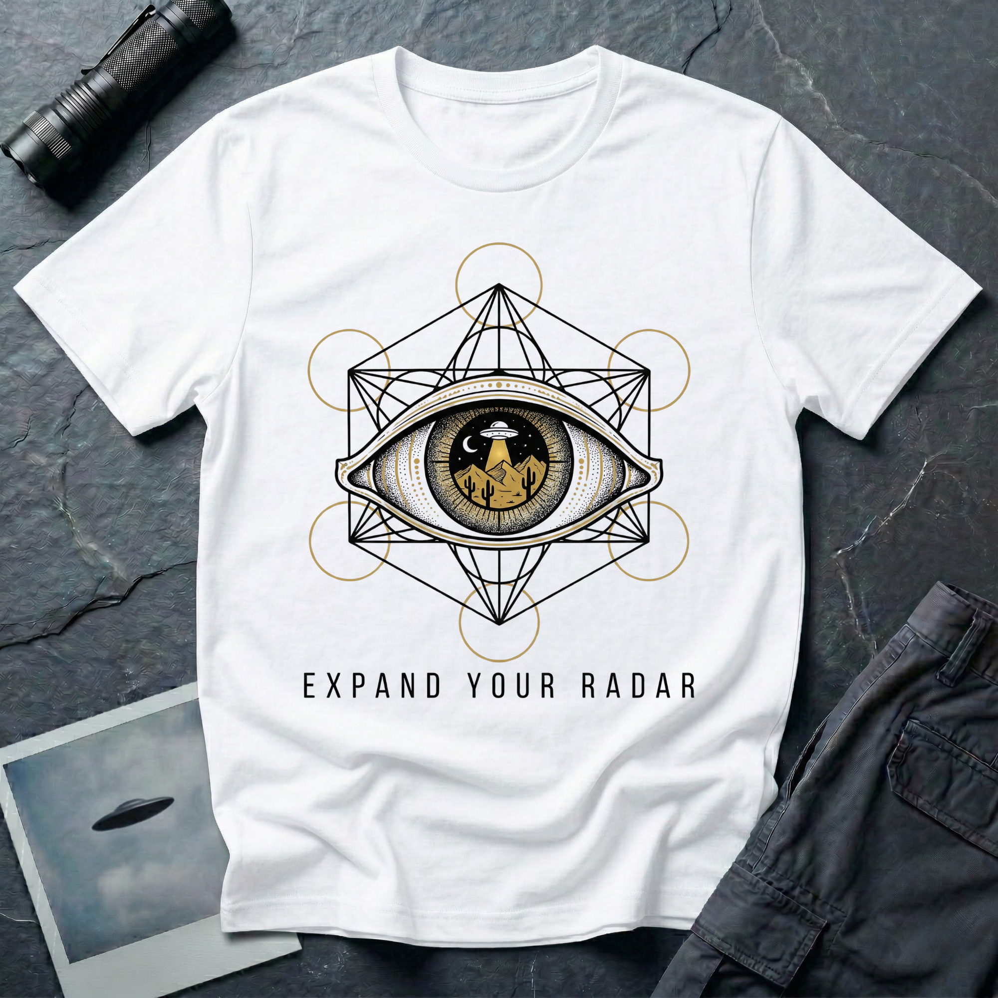 Expand Your Radar all seeing eye UFO t-shirt — sacred geometry frame around an eye containing a desert UFO encounter in gold and black linework on white cotton tee