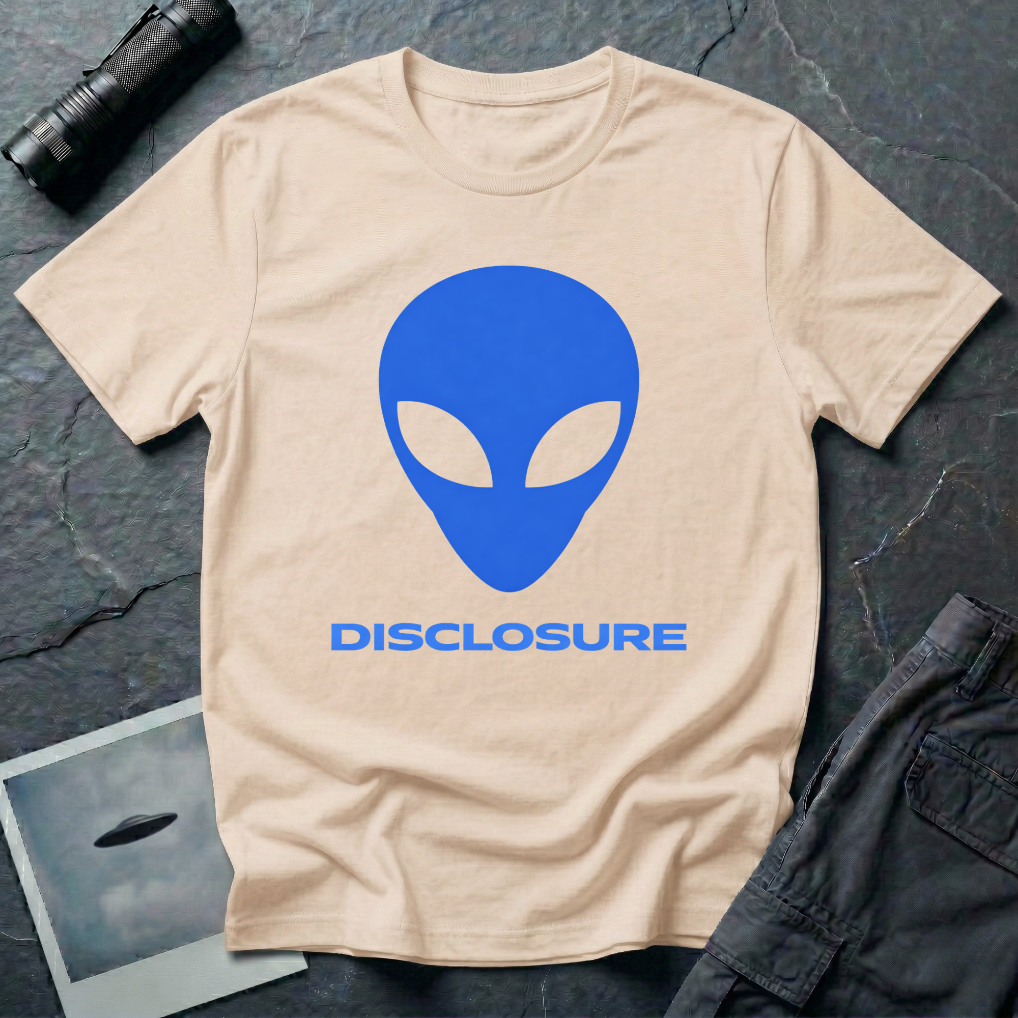 Alien Disclosure grey alien t-shirt — classic bulbous-head alien with almond eyes in electric blue on natural unisex cotton tee
