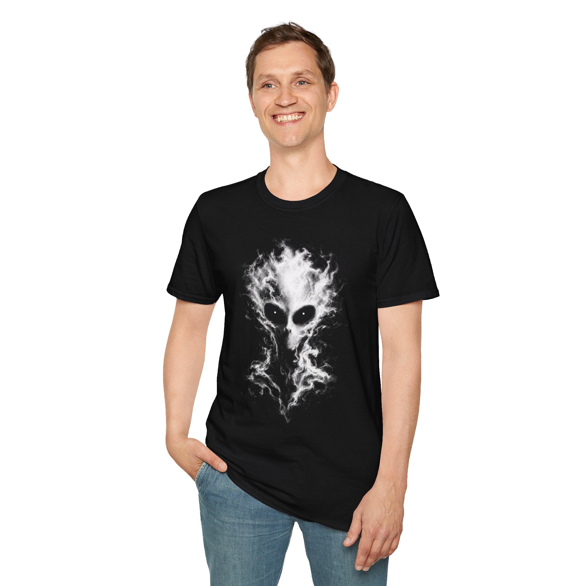 A man wearing a black short-sleeve t-shirt with a white and gray alien head graphic, paired with blue jeans, against a plain white background.