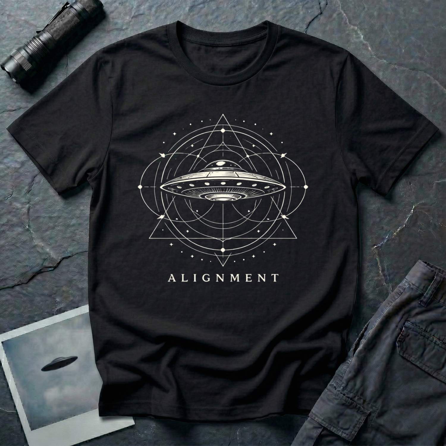 Alignment sacred geometry UFO t-shirt — flying saucer at the centre of a cosmological diagram with triangles and orbital rings in cream on black cotton tee