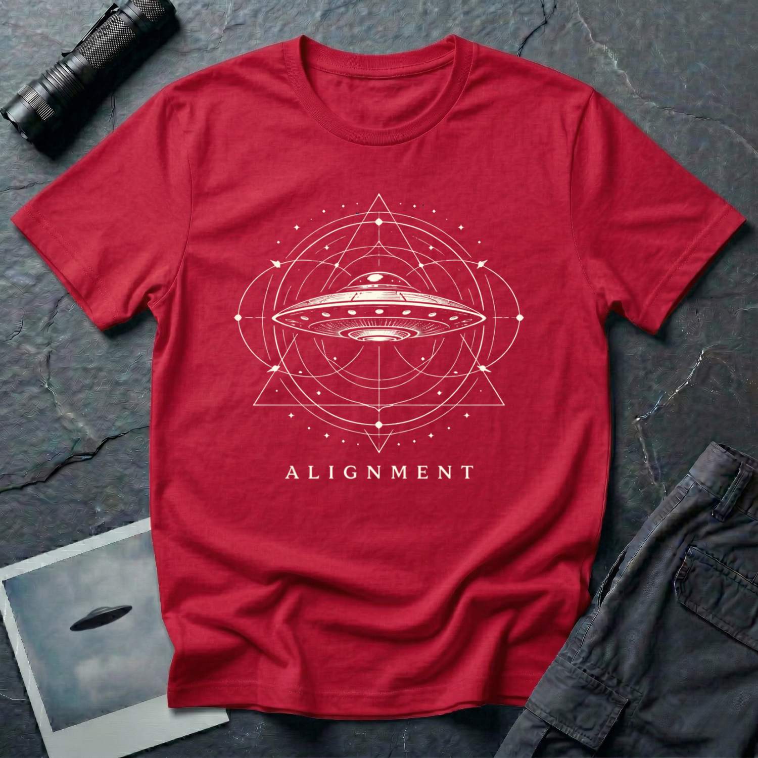 Alignment sacred geometry UFO t-shirt — flying saucer at the centre of a cosmological diagram with triangles and orbital rings in cream on red cotton tee