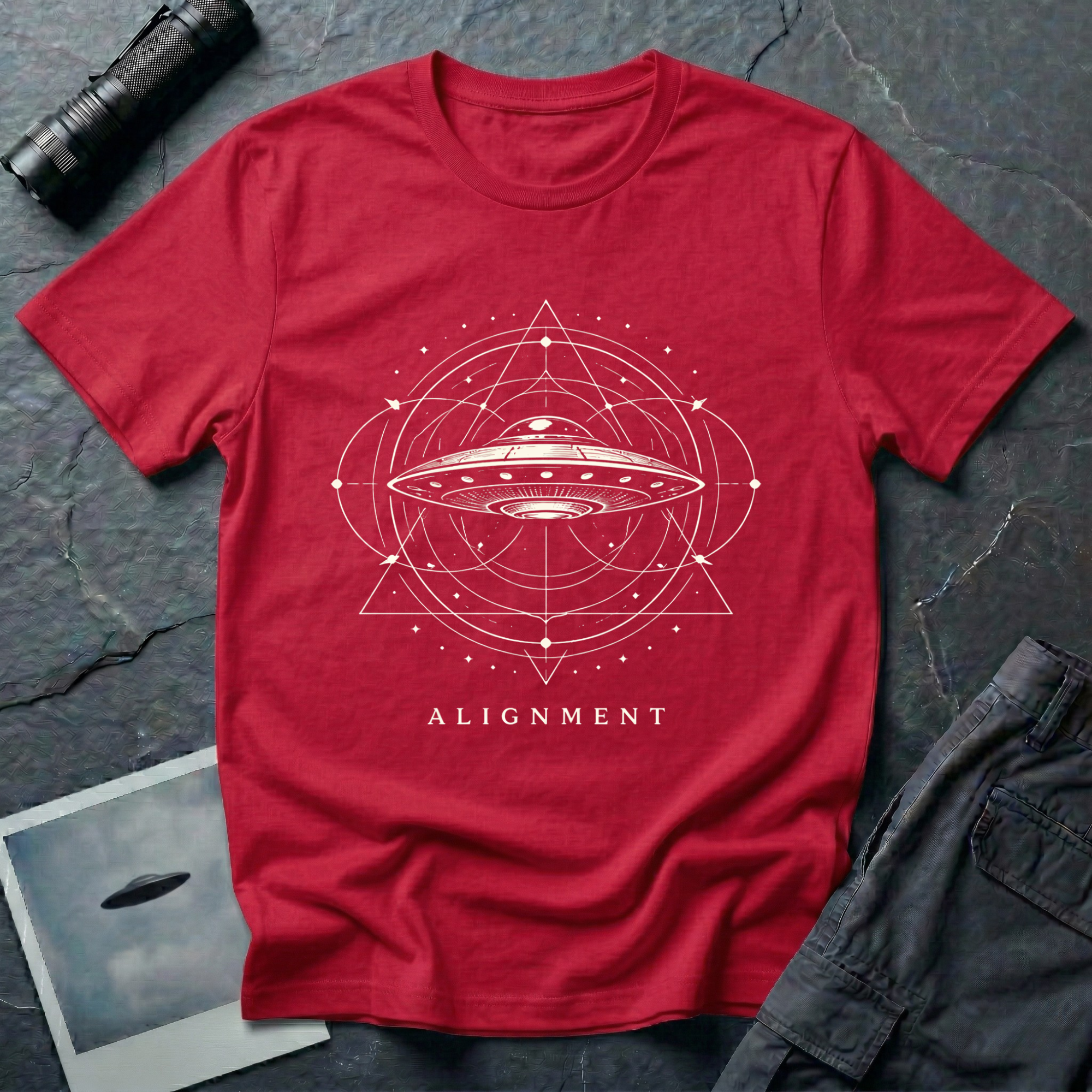Alignment sacred geometry UFO t-shirt — flying saucer at the centre of a cosmological diagram with triangles and orbital rings in cream on red cotton tee
